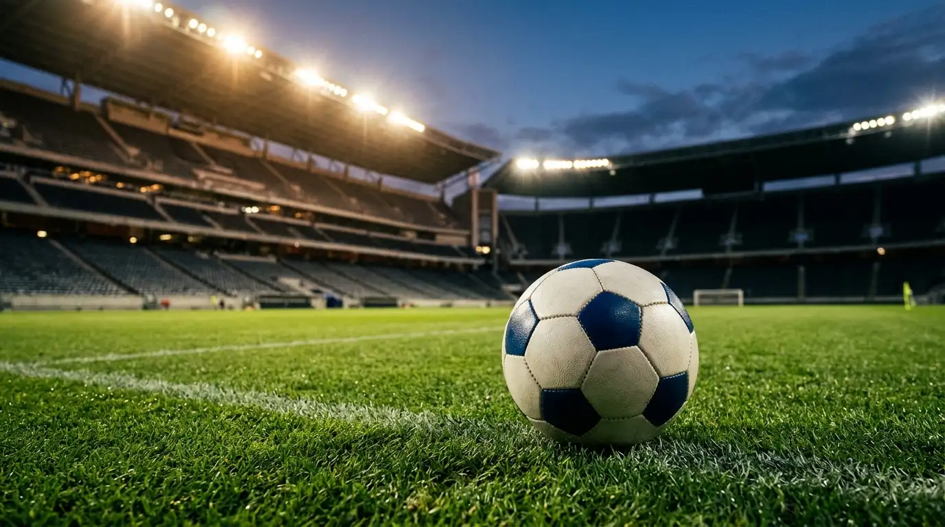 Balón oficial sobre el césped iluminado de un estadio al anochecer con los focos encendidos antes de un partido de eliminatoria del Mundial